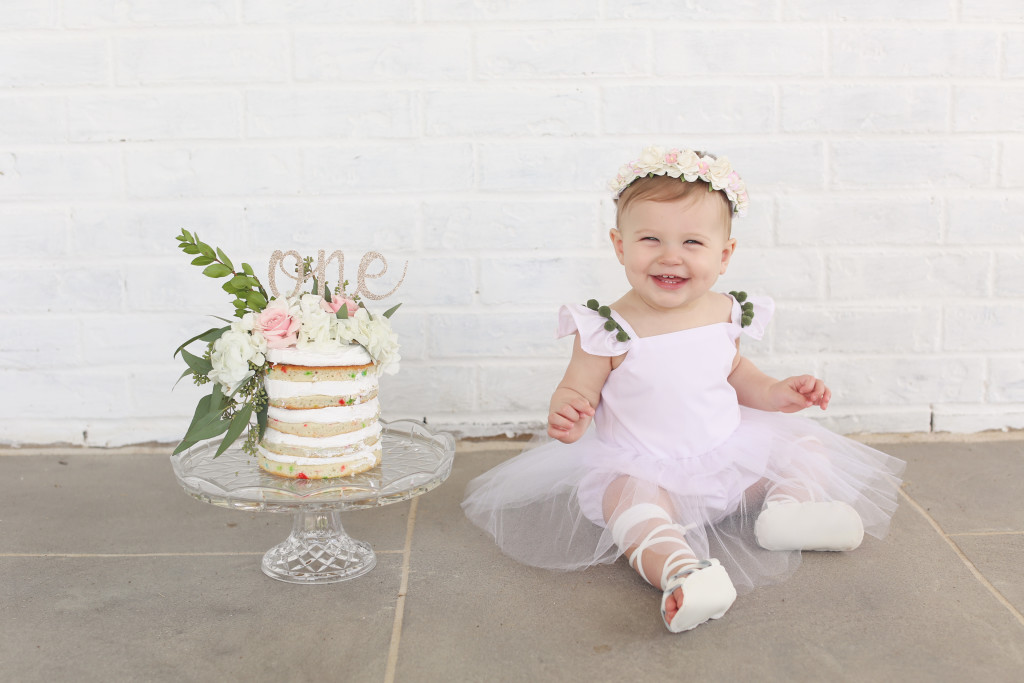 Lilyana's first birthday photoshoot and cake smash, featuring tutu romper with pompom trim from cuteheads